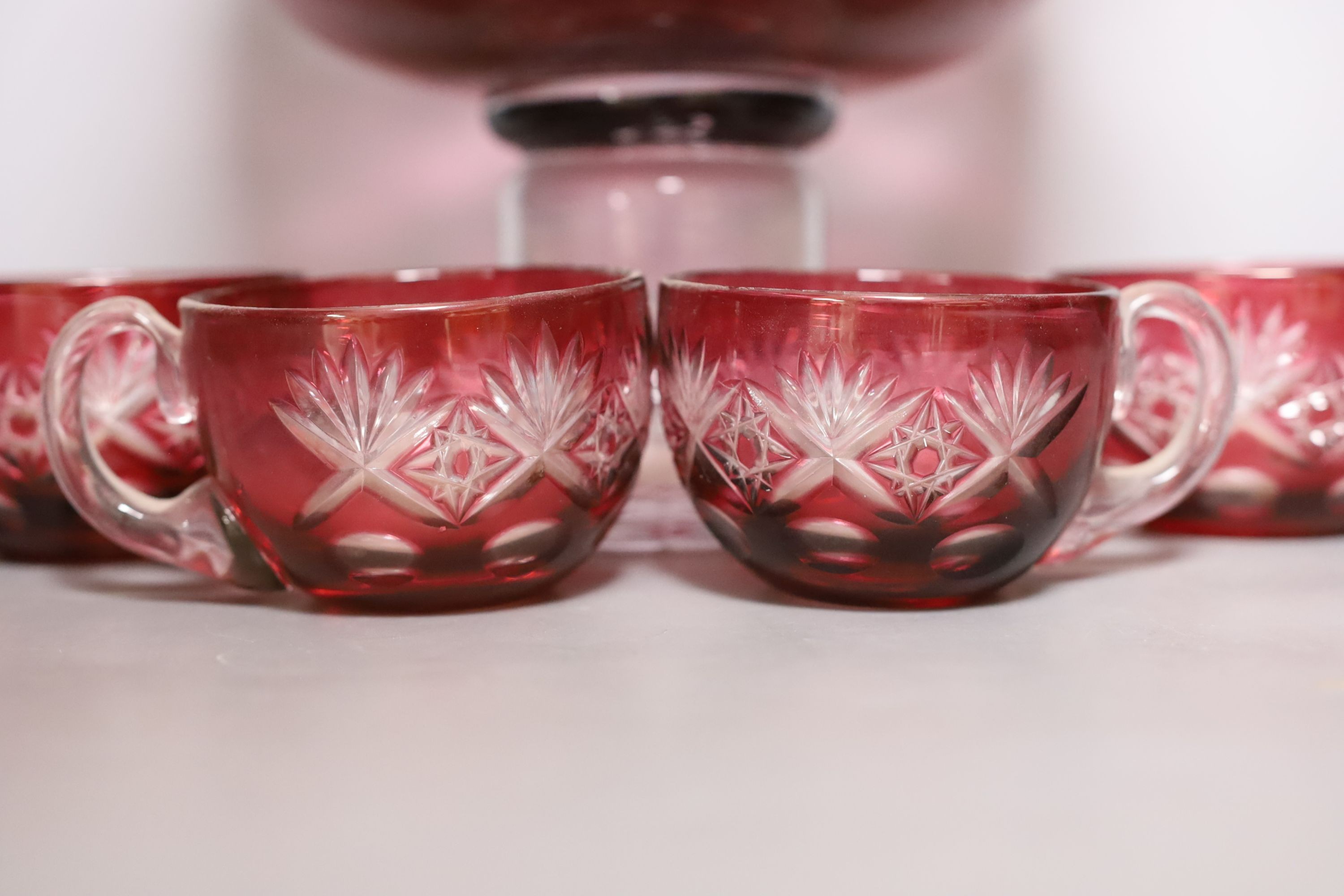 A Bohemian cut glass and cranberry overlay punch bowl with four glasses. Tallest 27cm